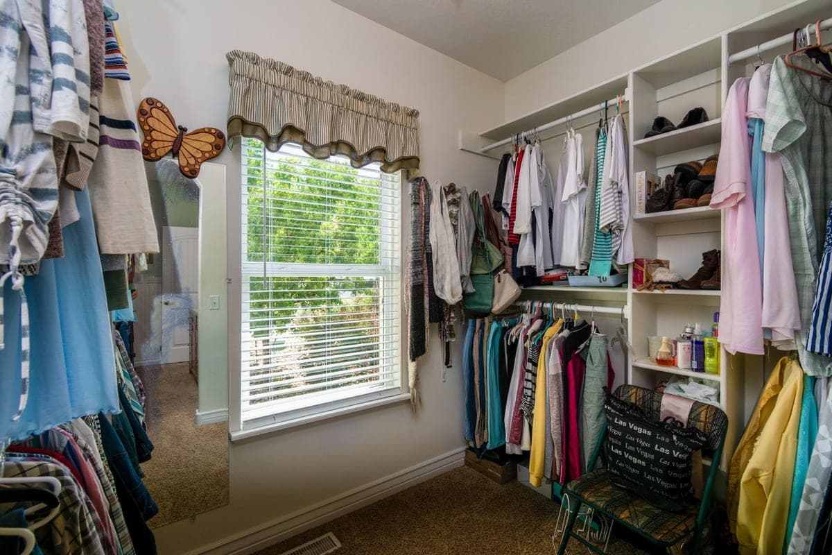 An organized walk-in closet with wire shelves and hanging clothes