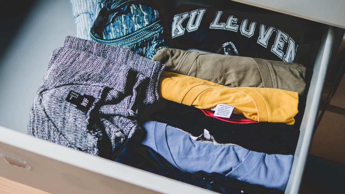 A drawer divided into sections holding folded clothes