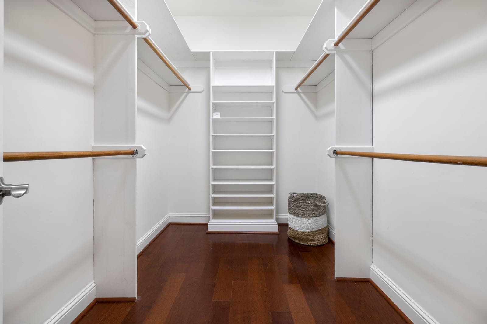 A white closet system with adjustable shelving and a hanging rod