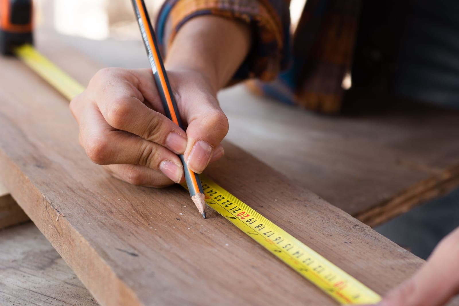 A tape measure and pencil resting on a timber board