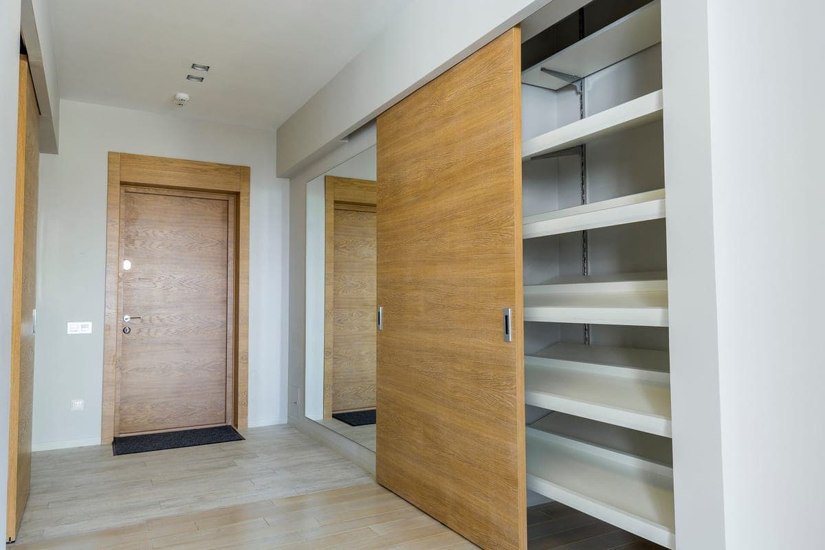 A reach-in bedroom closet with sliding doors and hanging clothes